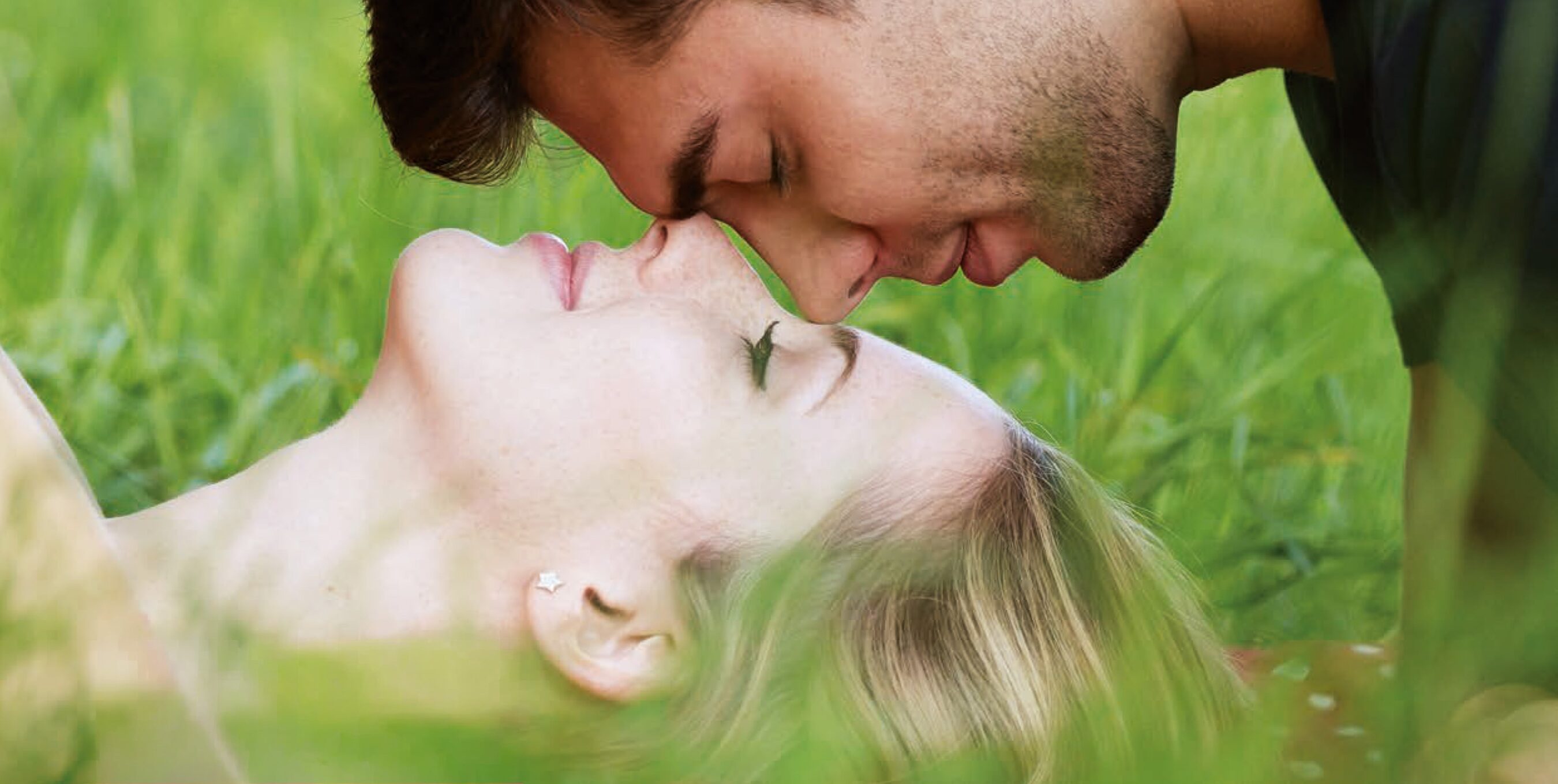 Frau und Mann liegen in romantischer Pose auf Wiese